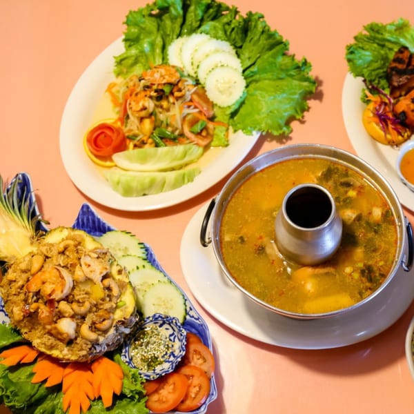 A vibrant spread of Thai dishes, including pineapple fried rice, soup, and salad.