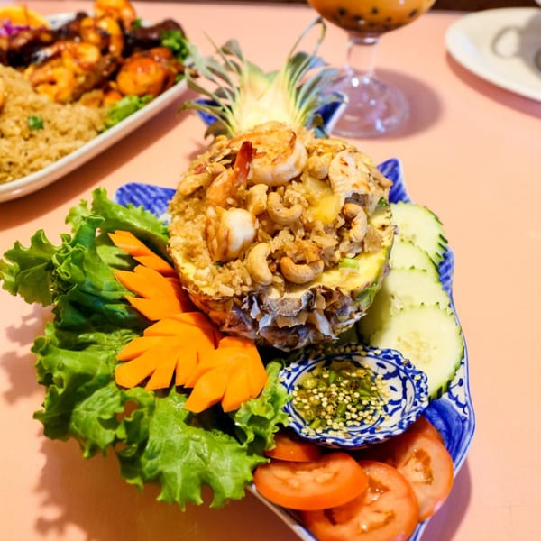 Pineapple fried rice with shrimp and cashews, garnished with lettuce, carrots, cucumbers, and tomatoes.